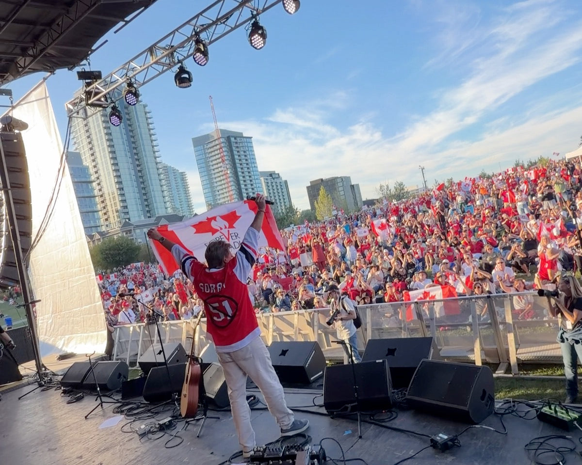 Thomas Lukaszuk raises the Forever Canadian flag over the crowd at the Calgary Concert for Unity